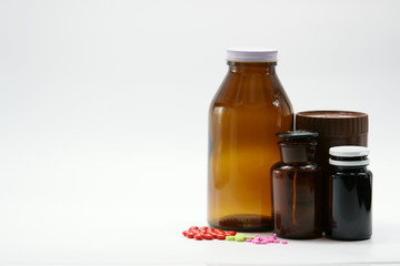 Pills and amber bottles with cap on white background