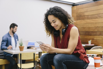 Young woman chatting with her smartphone in coworking espace