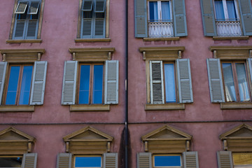Many windows. Medieval facade. Window shutters. Architectural style of Italy