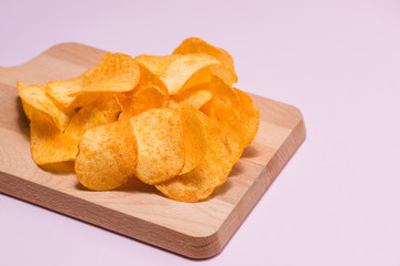 Salty crispy potato chips on cutting board.