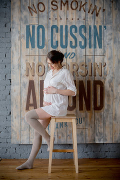 Portrait of a young pregnant woman in white shirt in photo Studio