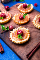 Apple caramel little tarts on wooden board and blue rustic background. French tatin with paradise apple. Close up.