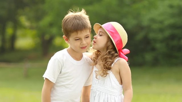 Little girl kisses the boy on the cheek, he is embarrassed and smiles. Slow motion
