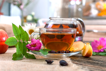 Tea with dried dog-rose and apple on a wooden table