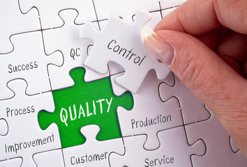 Quality Control - female hand with business puzzle green and white