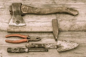 Old stained axe, hammer, pliers, trowel and screwdriver on old wooden surface
