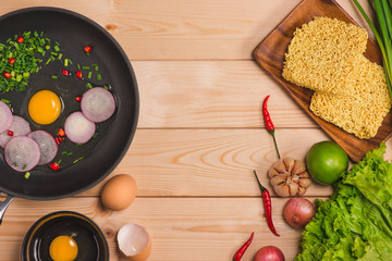 Instant noodles for cooking and eat in the dish with eggs and vegetables on wooden background.