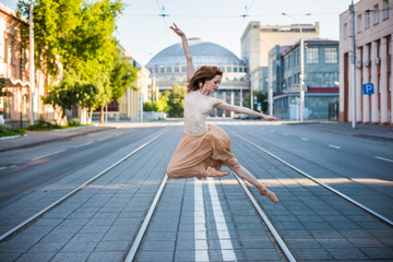 Obraz premium Ballerina in leotard and skirt and ballet shoes dancing on the street, jumps and bends