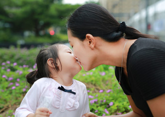 Mother and child girl kissing on bubble gum. Happy loving family.