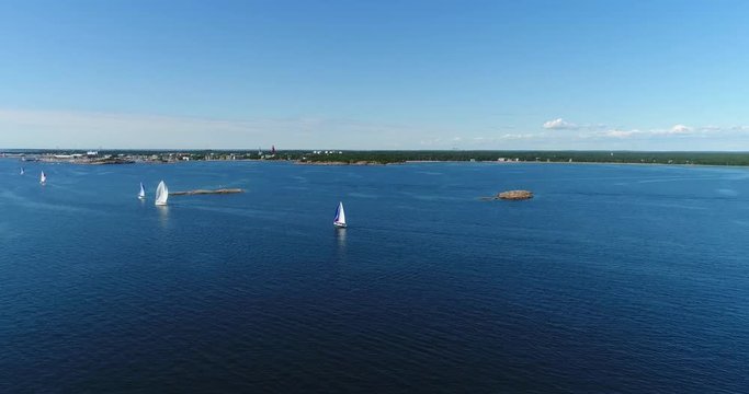 Sailboat regatta, Cinema 4k aerial view following sailboats above the baltic sea and towards hanko city, out on the turquoise sea, on hango regatta day, in the finnish archipelago of Hanko, Finland