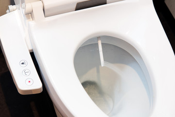 Toilet bowl with electronic control bidet. Water sprays from the toilet bowl. A cleansing jet of water designed to cleanse the anus of the user of this bidet-style toilet.  - obrazy, fototapety, plakaty