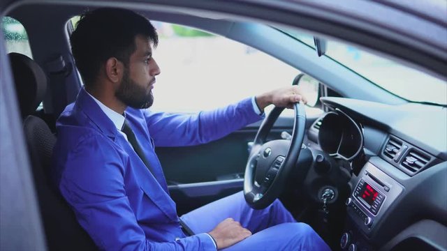 Handsome young muslim man driving the car and looking at the road. Modern muslim people.