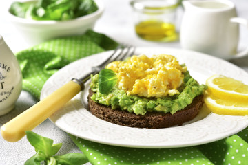 Rye toast with scrambled egg and avocado - concept of healthy breakfast.