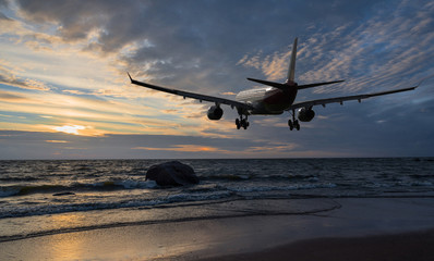Airplane flying over the sea at sunset