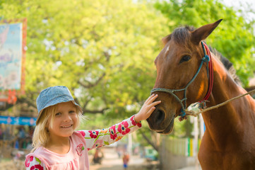 Adorable girl is playing with forse on farm