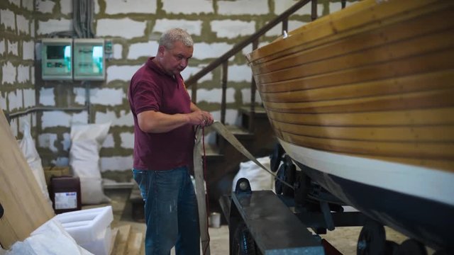 Mature master in spectacles with assistant working with homemade sailboat in workroom 4k. Hobby