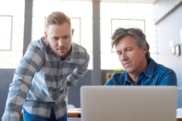Fototapeta premium Focused young businessmen using a laptop at an office desk
