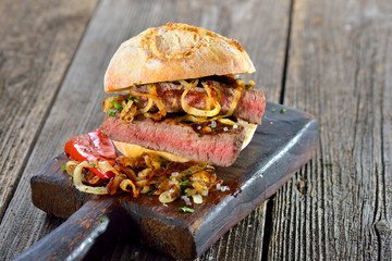 Gegrilltes Filetsteak vom Rind mit Röstzwiebel im reschen Brötchen serviert - Big meat sandwich:...