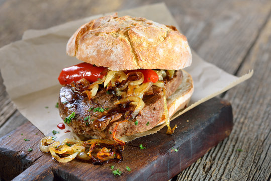 Gegrilltes Filetsteak vom Rind mit R&ouml;stzwiebel im reschen Br&ouml;tchen serviert - Big meat sandwich: Grilled beef fillet steak with fried onion rings on a fresh roll