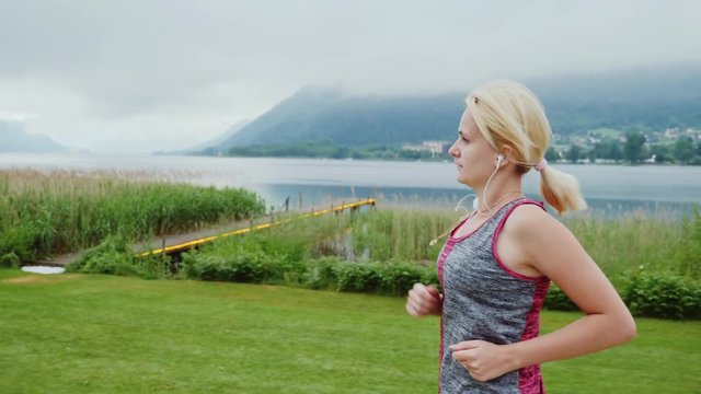 Morning jogging near a mountain lake in the Alps. Steadicam shot