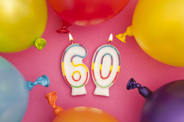 Happy Birthday number 60 celebration candle with colorful balloons