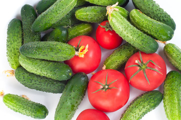 Fresh harvest of cucumbers and red tomatoes on a white background