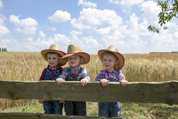 three little cowboys outdoors in a field