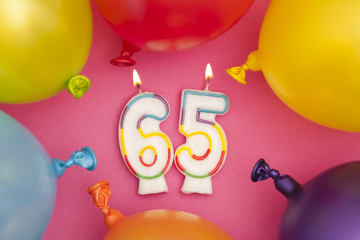 Happy Birthday number 65 celebration candle with colorful balloons