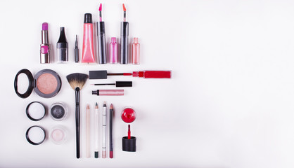 Colorful frame with various makeup products on a white background. Close up look at the mascara brushes and nail polish over a white background.