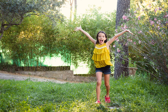 happy girl running in sprinkler water