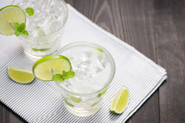 Fresh cocktail with lime, ice and mint on a rustic background. Copy space, top view