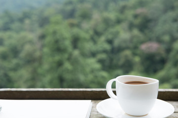 hot coffee in white cup on wood table with green nature background