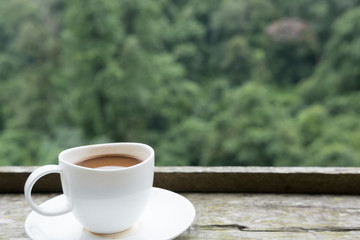 hot coffee in white cup on wood table with green nature background