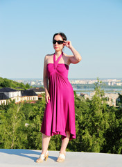 A woman is standing on the edge of a roof.