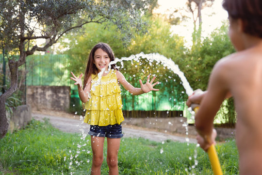 smiling girl being sprayed with hose