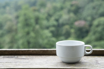 white tea cup on wood table with green nature background