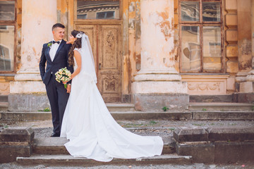 Beautiful romantic wedding couple of newlyweds hugging and kiss each other near old castle with columns and ancient door