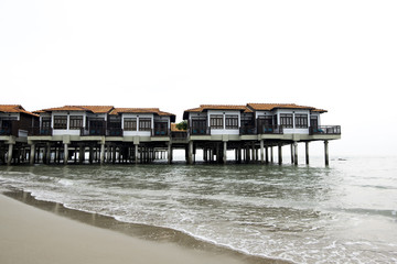 Travel holiday attraction, wooden modern design hotel on water over cloudy sky background.