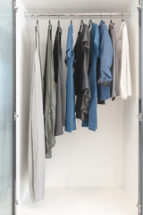 clothes hanging on rail in wooden white wardrobe