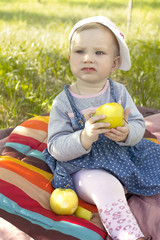 Маленькая девочка ест яблоко.