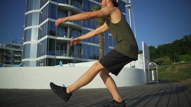 Athletic strong man pistol squats exercise seaside sunny pier rapid slow motion