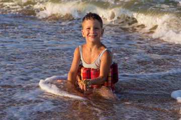 Little boy sitting in sea surf