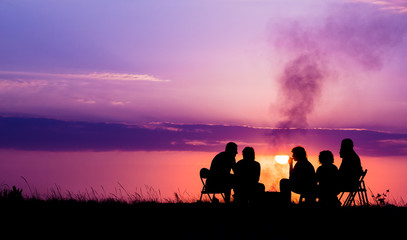 people sitting near campfire against sunset with copyspace - Powered by Adobe