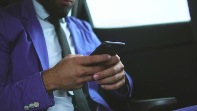 Close up view of modern muslim businessman in the car. He using smartphone and typing on it