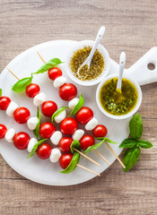 Appetizer in the form of caprese salad in the form of small shish kebabs for a summer healthy snack. On a wooden background