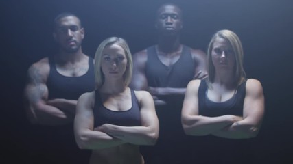 Group of athletes staring at the camera with their arms crossed on a foggy dark background