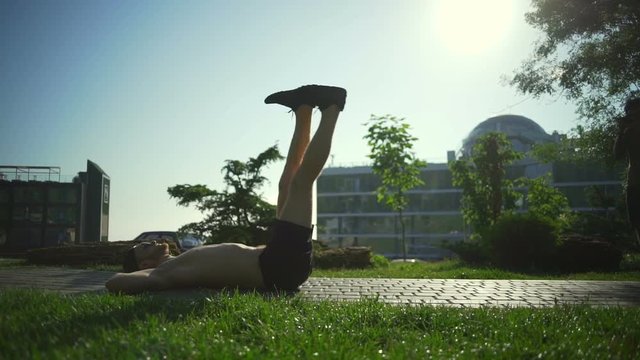 Strong young man do four times abs exercises sunny green park rapid slow motion