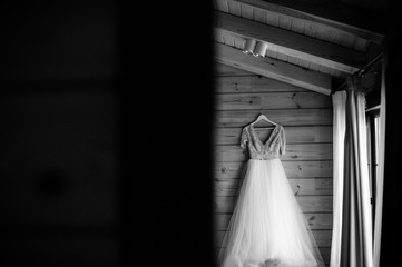 bridal dress hanging on wooden wall, black and white foto