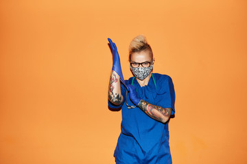Nurse in blue uniform wearing gloves against orange wall