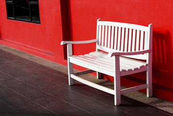 Fototapeta na wymiar Wood white bench beside the red wall background